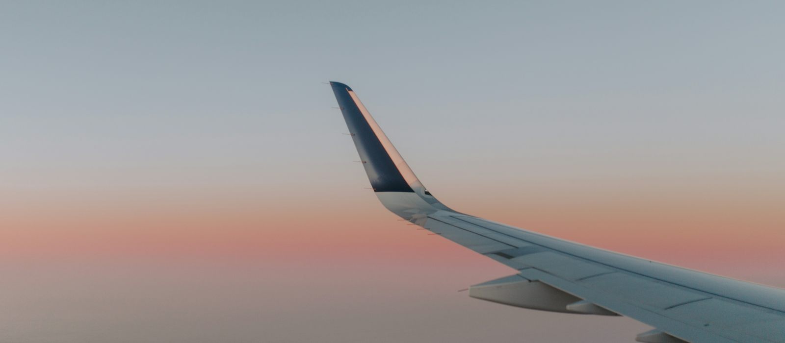 Airliner wing above the clouds at dusk
